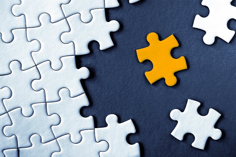 1134352187 Close-up view of white jigsaw puzzle pieces on grey background