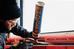 Ö-Normschu Arbeiter klebt etwas an einem Fenster